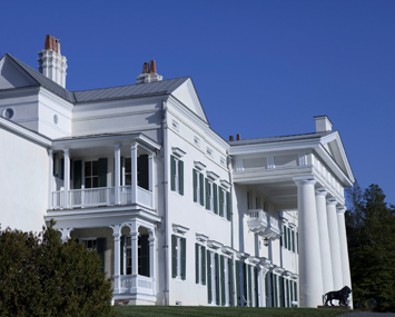 The exterior of a white mansion with clear blue skies.