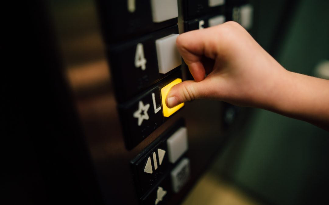 Person's hand pressing the Lobby button in an elevator