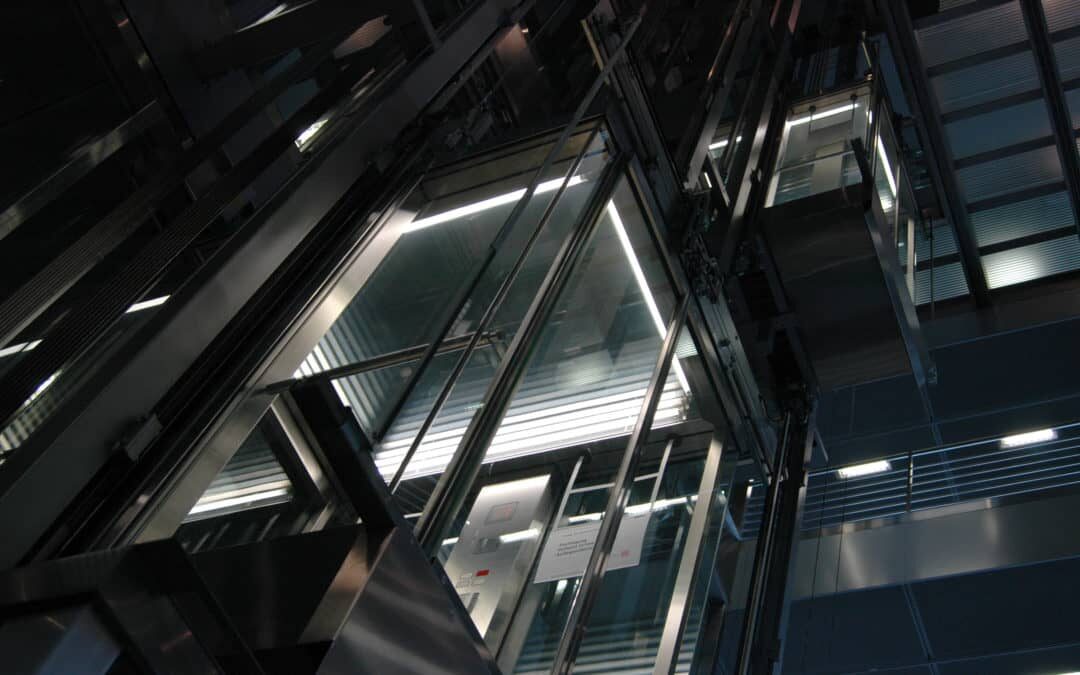 modern glass elevator lit up at night on the exterior of an urban building
