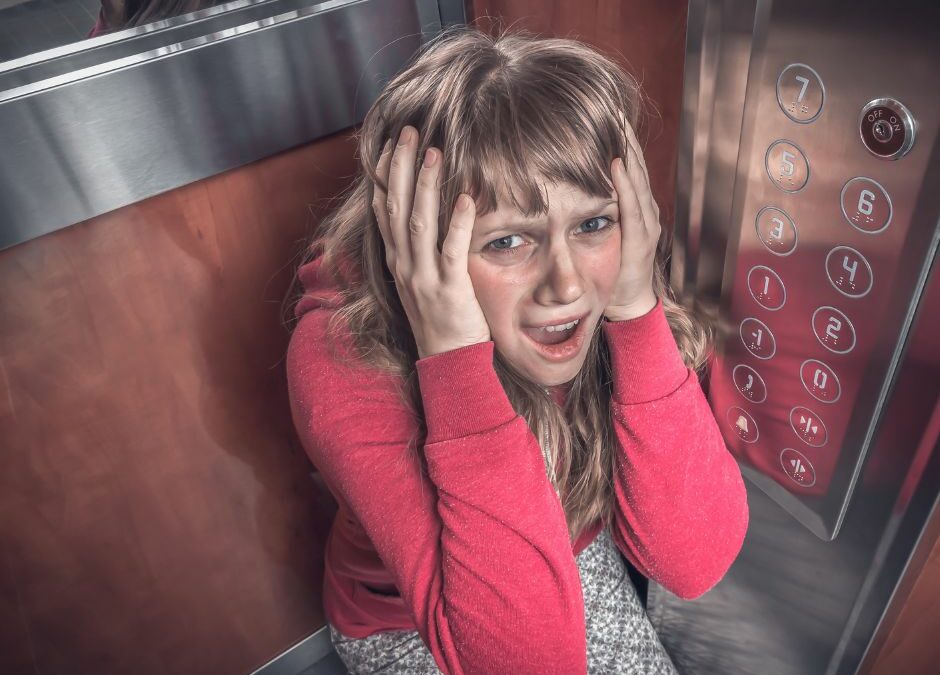A distressed passenger kneeling on the floor of a stuck elevator.