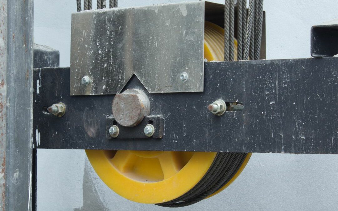 A close-up of an pulley and cables system for an elevator that needs maintenance.